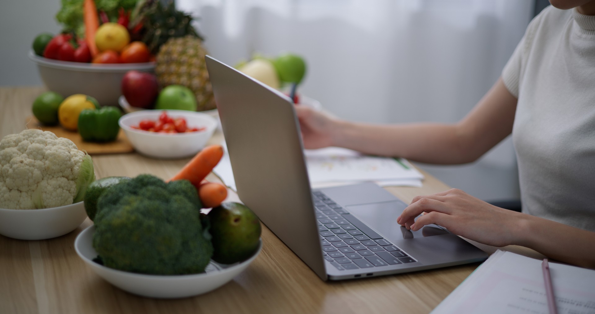 Young female Nutritionist working on laptop with healthy fruit and vegetable